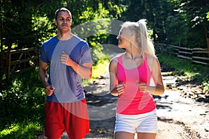 Running fitness couple of runners doing sport on road outdoor. Active living man and woman jogging training cardio