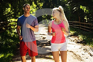 Running fitness couple of runners doing sport on road outdoor. Active living man and woman jogging training cardio