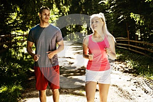 Running fitness couple of runners doing sport on road outdoor. Active living man and woman jogging training cardio