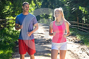 Running fitness couple of runners doing sport on road outdoor. Active living man and woman jogging training cardio
