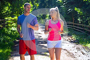 Running fitness couple of runners doing sport on road outdoor. Active living man and woman jogging training cardio