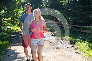 Running fitness couple of runners doing sport on road outdoor. Active living man and woman jogging training cardio