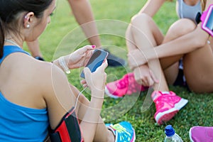 Running girls having fun in the park with mobile phone.