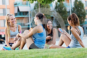 Running girls having fun in the park with mobile phone.