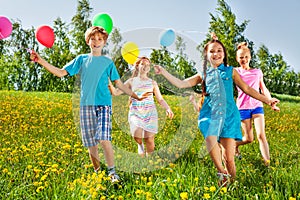 Running happy kids with balloons in green field