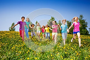 Running happy kids holding hands in green field