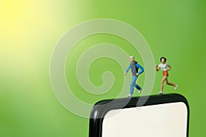 Running and jogging tracking app concept. A fat men women family running above smartphone. Miniature people figure photography.