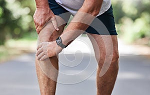 Running, knee pain and old man with hand on leg in park in for outdoor fitness and workout exercise. Health, wellness