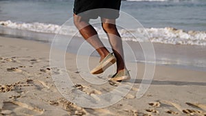 Running legs of active black senior man on beach with blue ocean water and waves on tropical islands. Elderly traveler