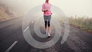 Running, legs and woman on road outdoor in forest, park or woods for exercise in winter. Morning, fog and person with