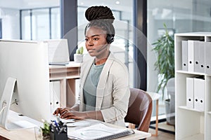 Running through a log of customer inquiries. a young call centre agent working on a computer in an office.