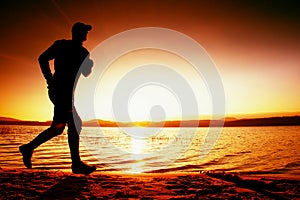 Running man on beach. Sportsman run in baseball capr, jogging guy during the sunrise