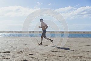 Running man jogging on beach.Muscular male runner training outside working out.