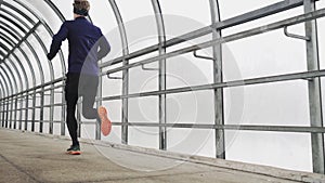 Running man in sportswear workout before triathlon, sprinting in glass tunnel.