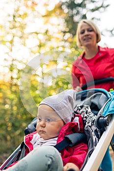 Running mother with stroller enjoying motherhood in autumn