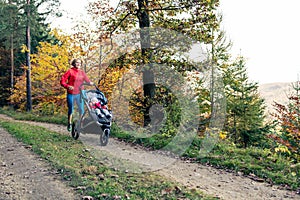 Running mother with stroller enjoying motherhood at autumn sunset