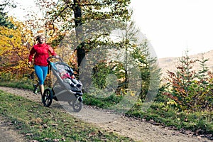 Running mother with stroller enjoying motherhood at autumn sunset