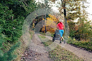 Running mother with stroller enjoying motherhood at autumn sunset