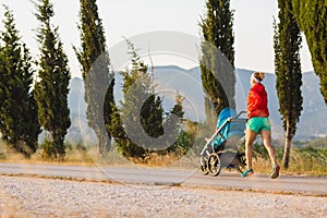 Running mother with stroller enjoying motherhood at sunset lands