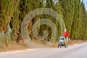 Running mother with stroller enjoying motherhood at sunset lands