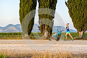 Running mother with stroller enjoying motherhood at sunset lands