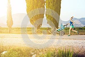 Running mother with stroller enjoying motherhood at sunset lands