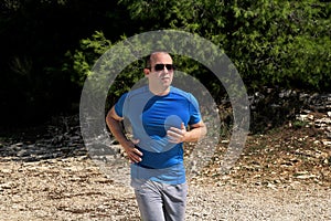 Running muscular man athlete runner training outdoor in forest. Running runner sportsmen wearing sportswear in cross country.