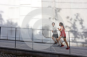 Running pair exercising outside in the city in an urban living active sport photo, with buildings in the background