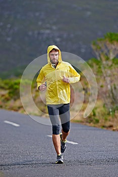 Running, rain and man with challenge, fitness and endurance with workout and cardio. Road, runner and athlete with
