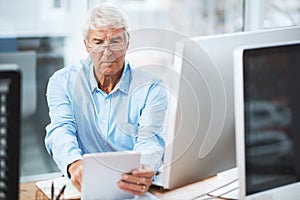 Running the rule over his business. a handsome senior businessman working on a tablet at home.