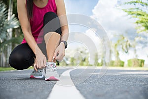 Running shoes - closeup of woman tying shoe laces. Female sport fitness runner getting ready for jogging in garden background