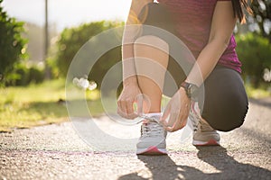 Running shoes - closeup of woman tying shoe laces. Female sport fitness runner getting ready for jogging in garden background