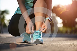 Running shoes - closeup of woman tying shoe laces. Female sport fitness runner getting ready for jogging in garden background