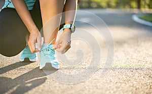 Running shoes - closeup of woman tying shoe laces. Female sport fitness runner getting ready for jogging in garden background