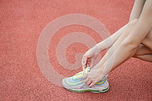 Running shoes - closeup of woman tying shoe laces. Female sport fitness runner getting ready for jogging outdoors on the lanes of