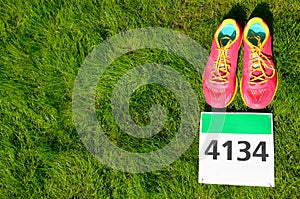 Running shoes and marathon race bib number on grass background, sport, fitness and healthy lifestyle