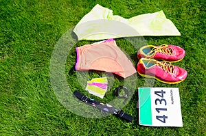 Running shoes, marathon race bib number, runners gear and energy gels on grass background, sport, fitness