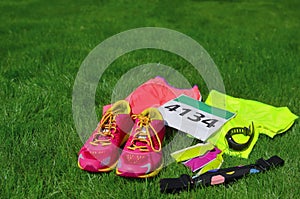 Running shoes, marathon race bib number, runners gear and energy gels on grass background, sport, fitness