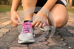 Running shoes - woman tying shoe laces. Closeup of female sport fitness runner getting ready for jogging outdoors on forest.