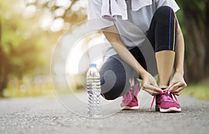 Running shoes - Woman tying shoe laces. Female sport fitness runner getting ready for jogging at garden