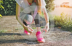 Running shoes - woman tying shoe laces. Female sport fitness runner getting ready for jogging outdoors on forest path in spring or