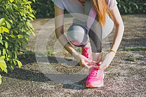 Running shoes - woman tying shoe laces. Female sport fitness runner getting ready for jogging outdoors on forest path in spring or