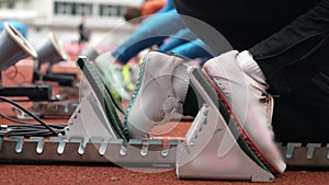 Running on a short distance, preparation for the start on the starting blocks, close-up of athletes' legs