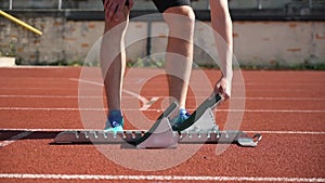 Running on a short distance, preparation for the start on the starting blocks, close-up of athletes' legs