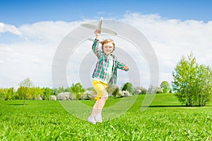 Running small boy holding airplane toy in meadow