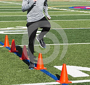 Running speed drills over orange cones on turf field