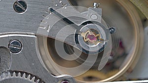 Running steel mechanical watch with focus on ruby stone on foreground