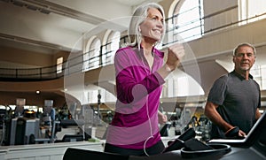 Running straight towards a healthier, happier lifestyle. a mature woman and man exercising on treadmills at the gym.