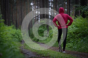 Running stretching. Athlete in the morning forest doing workout