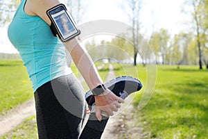 Running stretching - runner wearing smartwatch. Closeup of running shoes, woman stretching leg as warm-up before run.